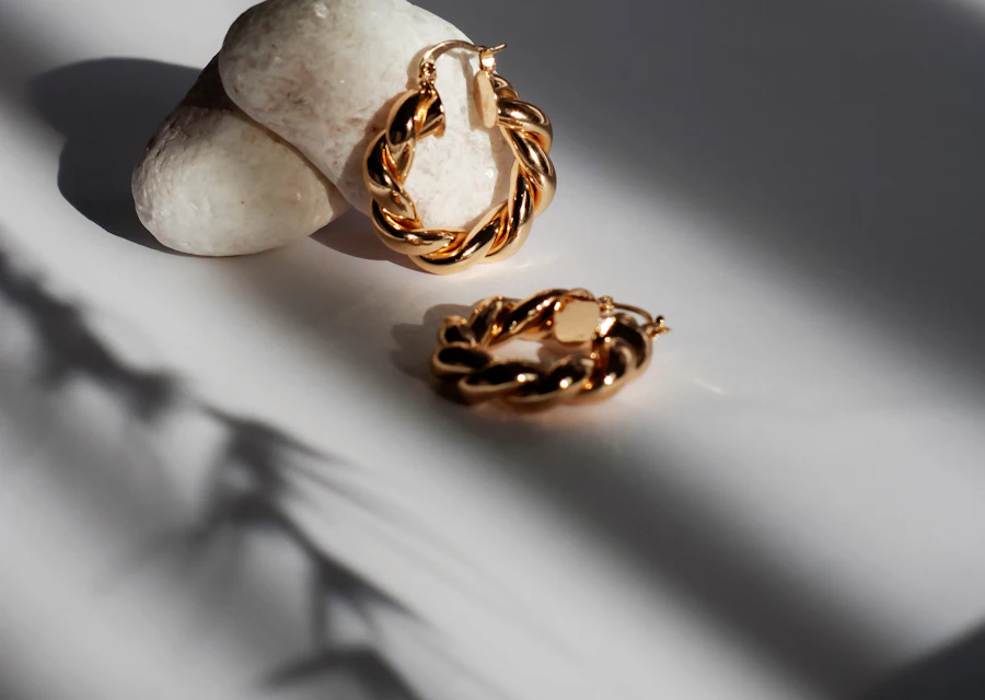 Gold twisted hoop earrings resting on white stones